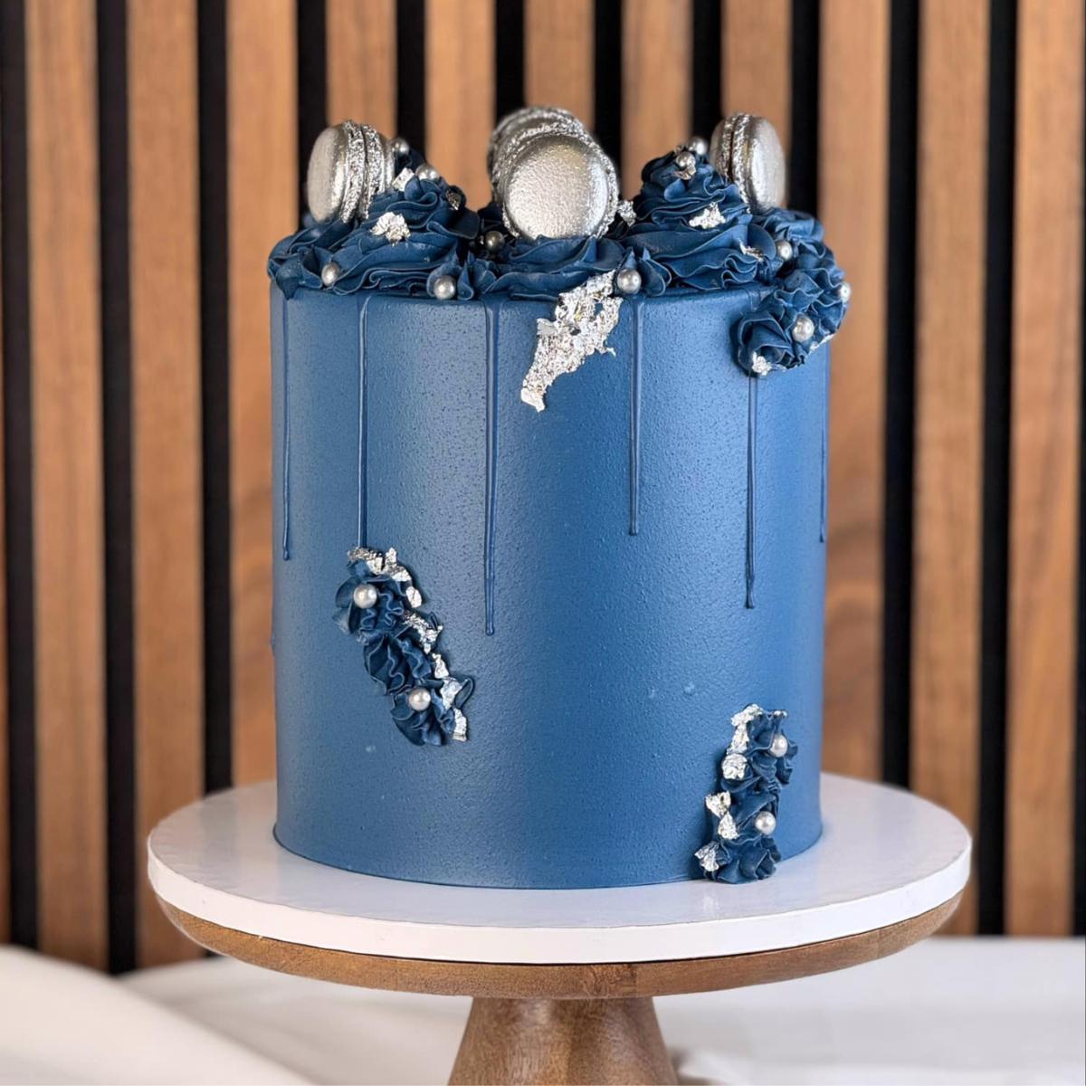 Midnight Elegance- Midnight Elegance Cake är en lyxig, djupt blå tårta dekorerad med skimrande silverdetaljer, handgjorda macarons och eleganta ätbara pärlor. Perfekt för sofistikerade evenemang som bröllop, galamiddagar eller födelsedagar, denna stilrena tårta kombinerar en minimalistisk design med exklusiva inslag som ger en tidlös känsla. ÄR DU ALLERGISK? KONTAKTA OSS OM ALLERGENER.040-104088 eller info@cocodrip.se -Cocodrip - Tårta och Baktillbehör