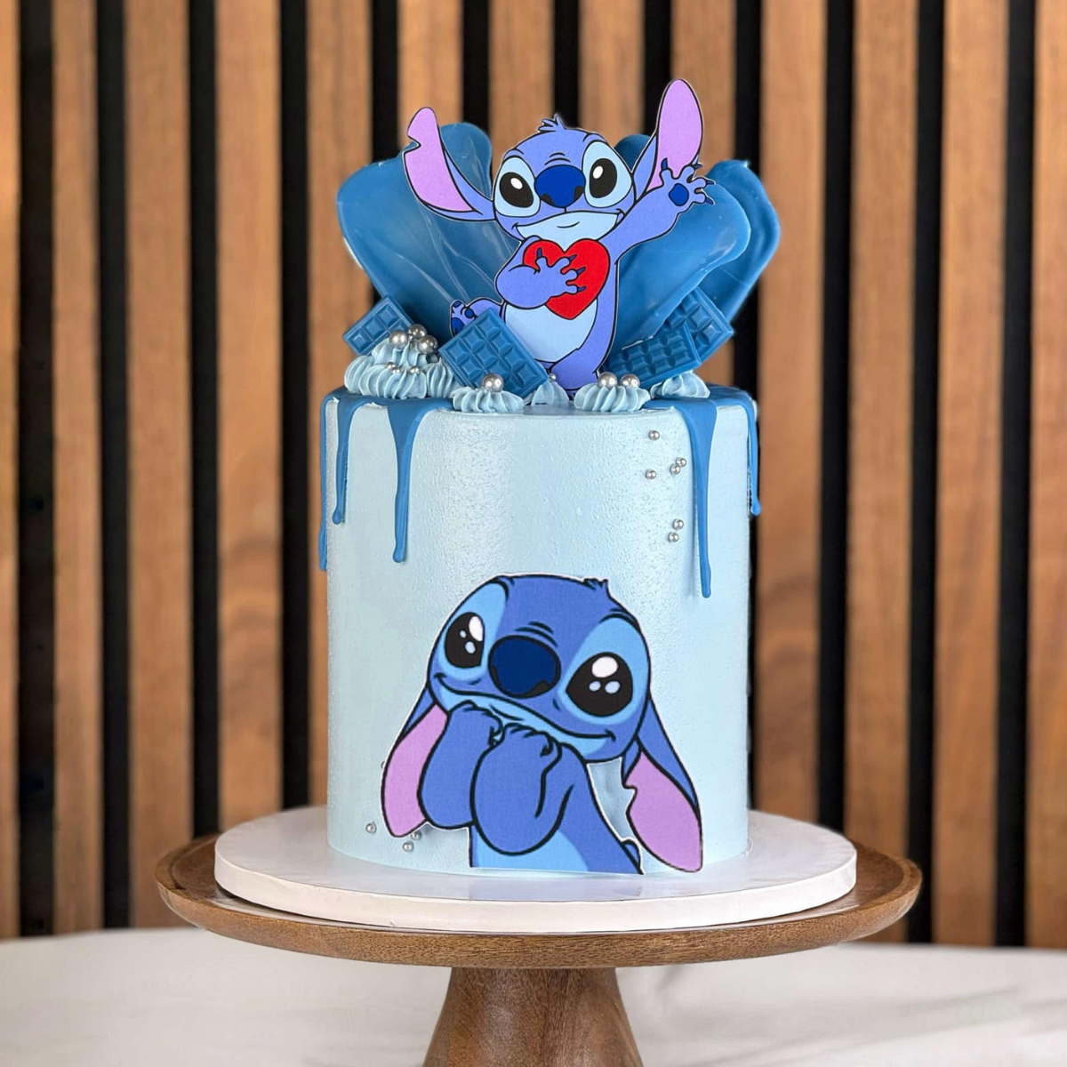 Stitch tårta- Denna underbara Stitch-tårta är perfekt för alla Disney- och Stitch-fans! Med en vacker ljusblå färg och en detaljerad dekor av Stitch-figurer är denna tårta ett fantastiskt val för barnkalas eller temafester. Tårtan är dekorerad med blå drip-effekt och eleganta sockerpärlor som ger en lyxig känsla. Beställ din unika och personliga Stitch-tårta hos oss och gör din fest oförglömlig! Bilderna är ej ätbara och plockas enkelt bort innan servering. ÄR DU ALLERGISK? KONTAKTA OSS OM ALLERGENER.040-10